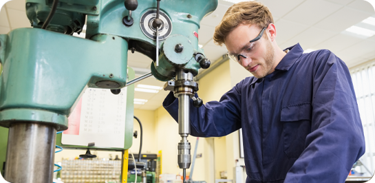 image of male student wearing safety glasses working on a machine.