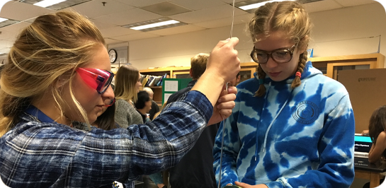 image of students wearing safety goggles conducting a science experiment.