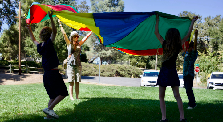 image of students and staff holding a parachute outside. 